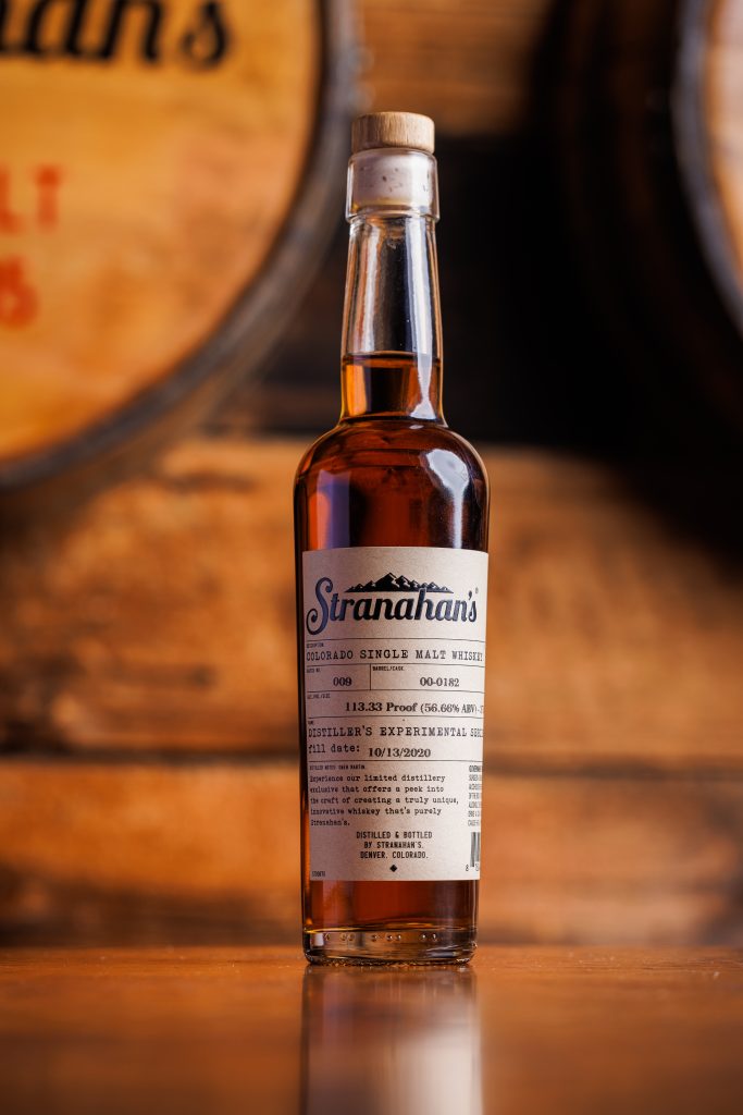 Stranahan's bottle in front of barrels